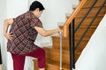 Asian senior older woman suffering from low-back lumbar pain while walking on stair at home