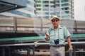Asian senior traveler standing outdoor in city with luggage beside while holding holding umbrella