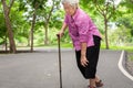 Asian senior woman arthritis,osteoarthritis,elderly people walking with walker in outdoor park,holding hand on the knee,feeling