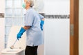 Asian senior woman in blue glove with medical mask cleaning toilet bowl using brush and detergent,female elderly hands touching Royalty Free Stock Photo