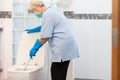 Asian senior woman in blue glove with medical mask cleaning toilet bowl using brush and detergent,female elderly housekeeper with Royalty Free Stock Photo