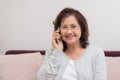 Asian senior woman cheerfully chatting with friends on mobile ph Royalty Free Stock Photo