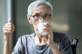 Asian senior woman drinking fresh milk from the glass,old elderly holding glass of milk,showing thumb up while drinking and Royalty Free Stock Photo