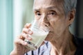 Asian senior woman drinking warm fresh milk from glass in the morning at home,old elderly eat foods that are beneficial to the