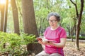 Asian senior woman in glasses and reading book in the park Royalty Free Stock Photo