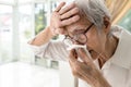 Asian senior woman had nosebleed,epistaxis,stop blood wipe her nose with tissue paper,touches forehead with hand to check,measure Royalty Free Stock Photo