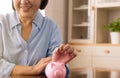 Asian senior female hands putting coin to piggy bank for retirement,Saving money concept