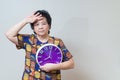 Asian senior woman holding purple clock in studio shot, specialt Royalty Free Stock Photo