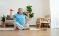 Asian senior woman lifting dumbbell for exercise and workout at home. Active mature woman doing stretching exercise in living room Royalty Free Stock Photo