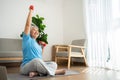 Asian senior woman lifting dumbbell for exercise and workout at home. Active mature woman doing stretching exercise in living room