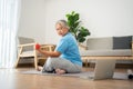 Asian senior woman lifting dumbbell for exercise and workout at home. Active mature woman doing stretching exercise in living room