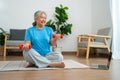 Asian senior woman lifting dumbbell for exercise and workout at home. Active mature woman doing stretching exercise in living room Royalty Free Stock Photo