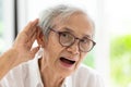 Asian senior woman listening by handÃ¢â¬â¢s up to the ear,having difficulty in hearing,elderly woman hard to hear,wear glasses with
