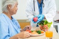 Asian senior woman patient eating Salmon steak breakfast with vegetable healthy food while sitting and hungry on bed in hospital Royalty Free Stock Photo