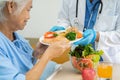 Asian senior woman patient eating Salmon steak breakfast with vegetable healthy food while sitting and hungry on bed in hospital Royalty Free Stock Photo