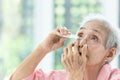 Asian senior woman putting eye drop,closeup view of elderly person using bottle of eyedrops in her eyes,sick old woman suffering Royalty Free Stock Photo