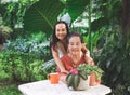 Asian senior woman sitting with her daughter  at white table in beautiful garden, daughter hugging her mother from the back, Royalty Free Stock Photo