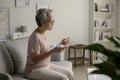 Asian senior woman sitting on sofa in her living room reading the information sheet of her prescribed medicine. Royalty Free Stock Photo