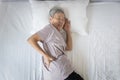 Asian senior woman suffering from backache,sore waist while sleep,unhappy old elderly feeling discomfort pain in her back muscles Royalty Free Stock Photo