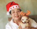 Asian senior woman wearing red Christmas hat  holding  her Chihuahua dog wearing reindeer  hat Royalty Free Stock Photo