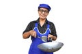 Asian senior woman, wears blue apron and cap, holds frying pan and spatula or ladle. Royalty Free Stock Photo