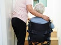 Asian senior woman on wheelchair with caregiver help support walking down the stairs prevent accident, slip and fall at home Royalty Free Stock Photo