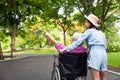 Asian senior woman in wheelchair with little child girl supporting disabled grandparent on walking green nature,grandmother and