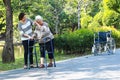 Asian senior woman use walking aid during rehabilitation after knee surgery, young carer assisting reassuring elderly people