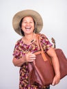 Asian senoir woman laughing while carrying ukulele and big brown