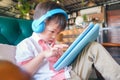 Asian serious toddler boy child sitting in armchair playing game, watching a video from digital tablet pc Royalty Free Stock Photo