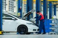 Asian servicing mechanic pouring new oil lubricant into the car engine in the auto repair center Royalty Free Stock Photo