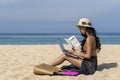 Asian sexy woman in bikini, using laptop computer and holding book on a beach, travel of summer vacation. Freelance work concept Royalty Free Stock Photo