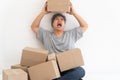 Asian Shopaholic man Shocked and sitting on the floor in the living room and Cardboard Box on top of him after The courier