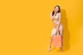 Asian shopaholic woman carrying shopping bags in colorful orange and yellow background Royalty Free Stock Photo