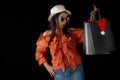 Asian shopping woman surprised with Black Friday shopping bag and Santa Claus hat inside on black background. Shopaholics and