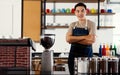 Asian short black hair young successful handsome male barista wear brown shirt and blue jeans bib apron stand smiling behind Royalty Free Stock Photo