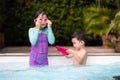 Asian sibling girl and boy playing water with toy together in the swimming pool with fun.