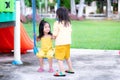 Asian sibling girl playing in the playground. The older sister stood talking to the sister sitting on the swing. Royalty Free Stock Photo