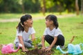 Asian sibling planting young tree on black soil together as save world in garden on summer day. Planting tree. Childchood and