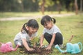 Asian sibling planting young tree on black soil together as save world in garden on summer day. Planting tree. Childchood and