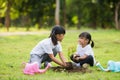 Asian sibling planting young tree on black soil together as save world in garden on summer day. Planting tree. Childchood and