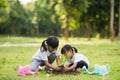 Asian sibling planting young tree on black soil together as save world in garden on summer day. Planting tree. Childchood and