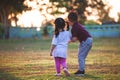 Asian siblings big brother and young sister holding hand and playing in the park together at sunset time