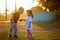 Asian siblings big brother and young sister holding hand and playing in the park together at sunset time