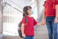 Asian siblings of primary school go hand in hand. sister and girl with backpack behind the back. Beginning of lessons. First day Royalty Free Stock Photo