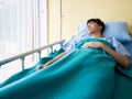 Asian sick man waiting for family or friend visit while sleeping on the bed with green blanket in the hospital Royalty Free Stock Photo