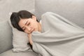 Asian Sick woman covered with a blanket lying in bed with high fever and a flu.