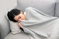 Asian Sick woman covered with a blanket lying in bed with high fever and a flu.