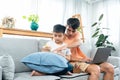 Asian single father is sitting with his son on sofa in living room of house, son was sitting