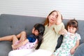 An Asian single mom is having a headache with her two young daughters sitting on the sofa Royalty Free Stock Photo